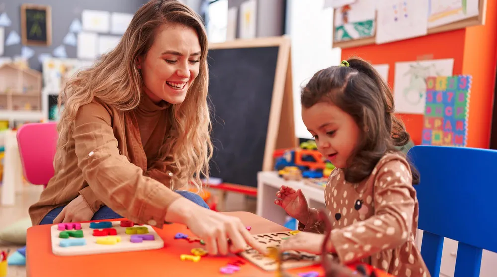 Éducatrice et enfant en atelier de manipulation à une table